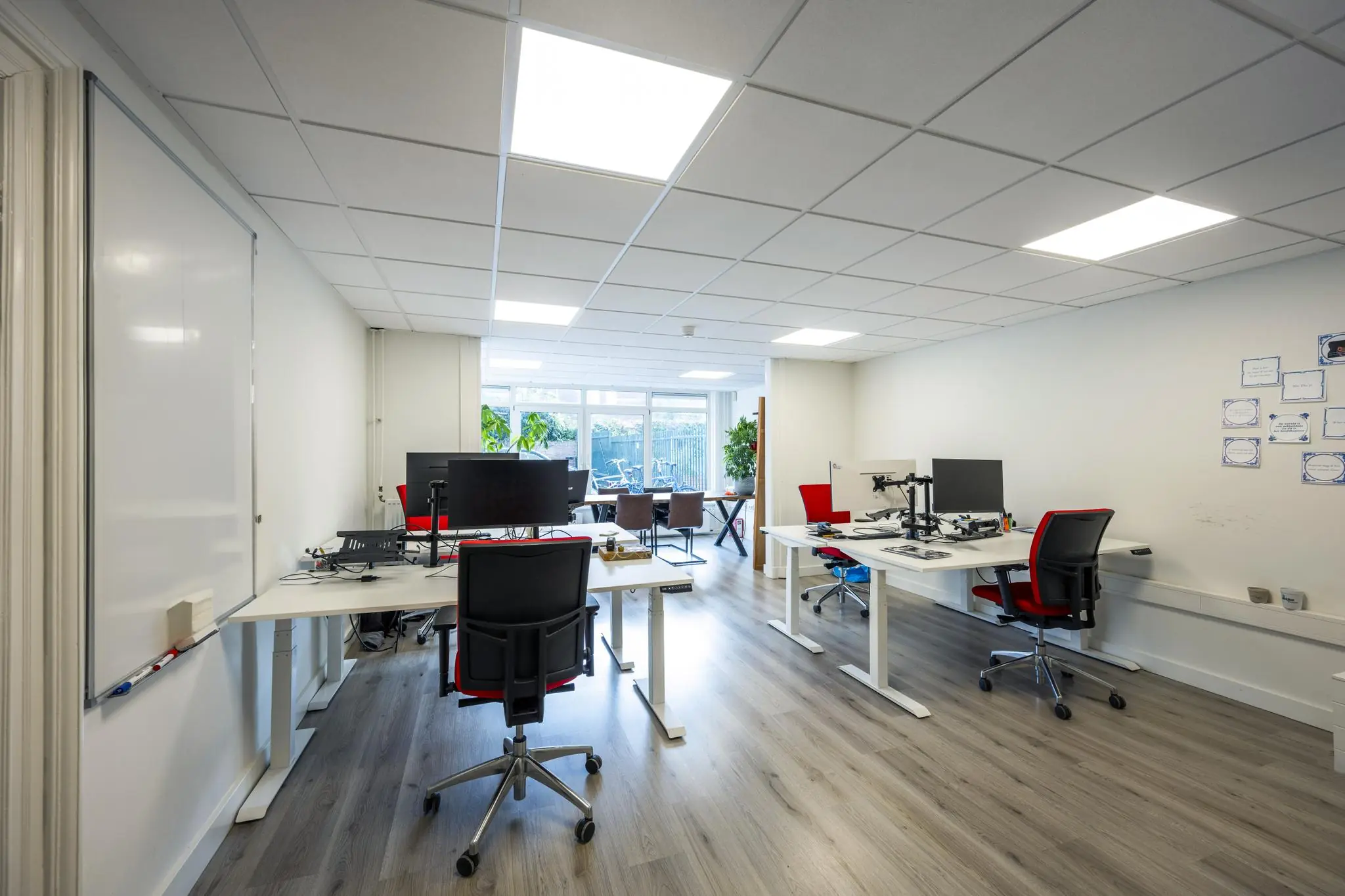 Moderne kantoorruimte aan de Nieuwe Gracht met verstelbare bureaus, computerschermen en veel natuurlijk licht.